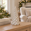 Ivory ceramic pinecone Christmas tree displayed on an oak shelf beside neutral books