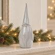 Large textured ceramic gonk on a limestone mantel with pine and Christmas lights