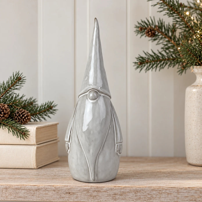 Large pale grey ceramic gonk styled on a shelf with cream books and evergreen foliage