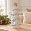 Large glazed ceramic Christmas tree with cream star on oak console with pinecones