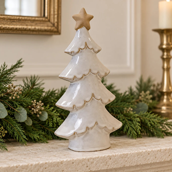 Stone-glazed ceramic tree with cream star on a mantel with Christmas greenery