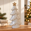Large ceramic Christmas tree styled on an oak shelf with neutral festive decor