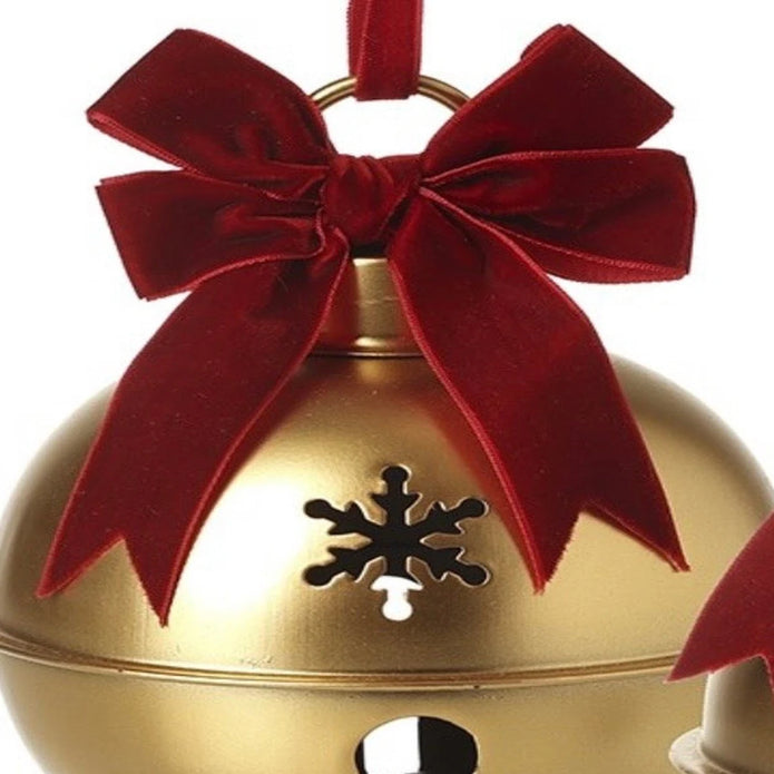 Close-up of gold Christmas bell with burgundy velvet bow and snowflake cut-out detail