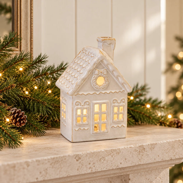 Ceramic LED Christmas house glowing on a limestone mantel