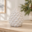 Large ivory glazed ceramic pinecone on an oak console with subtle Christmas greenery