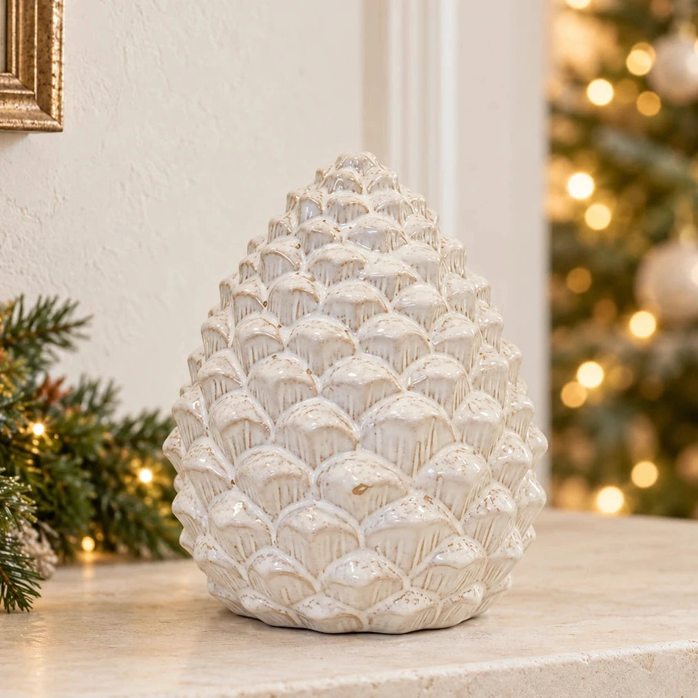Large ceramic pinecone decoration on a limestone mantel in a neutral Christmas room