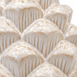 Close-up of overlapping ridged scales and ivory glaze on the ceramic pinecone