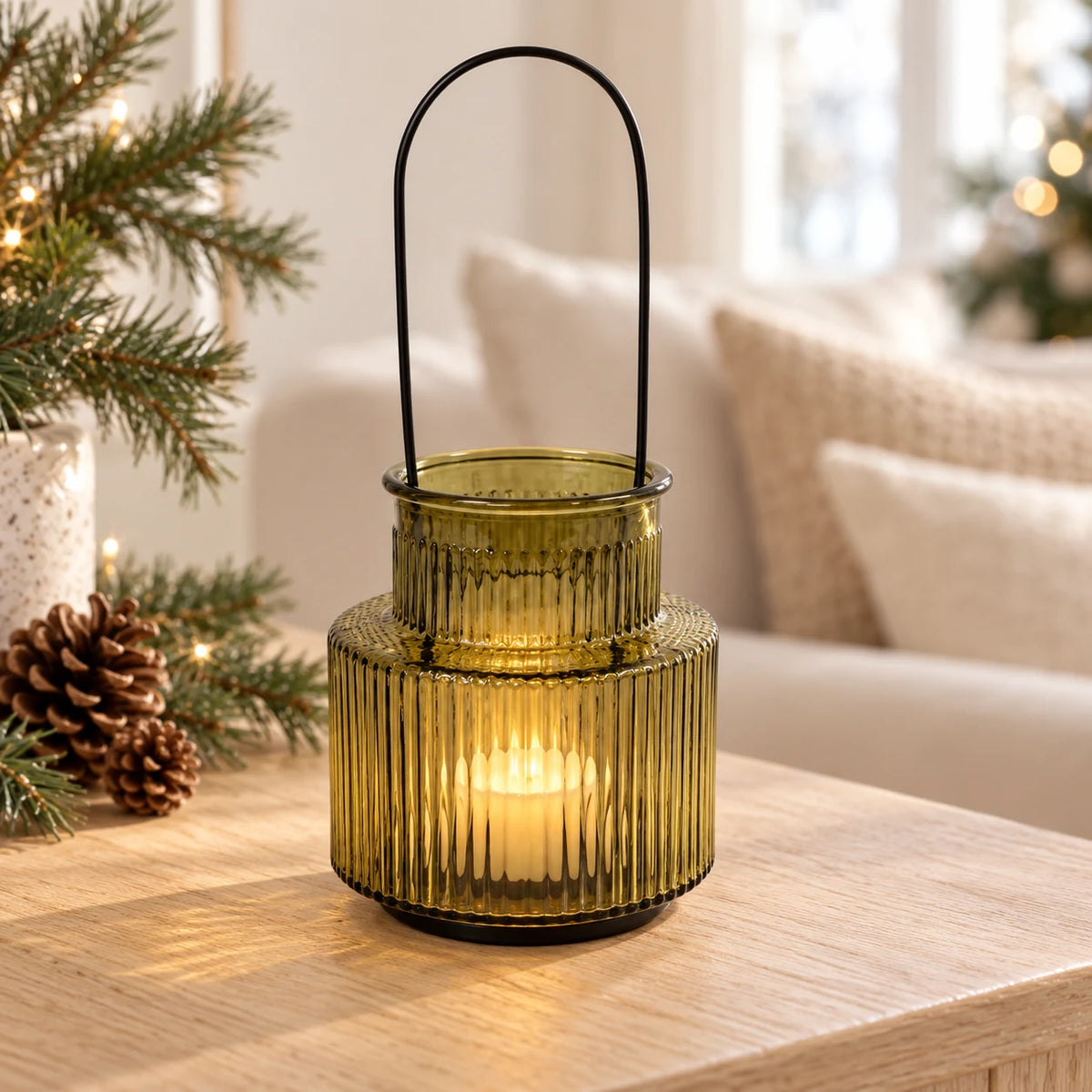 Large olive green ribbed glass candle holder with black handle on a Christmas console