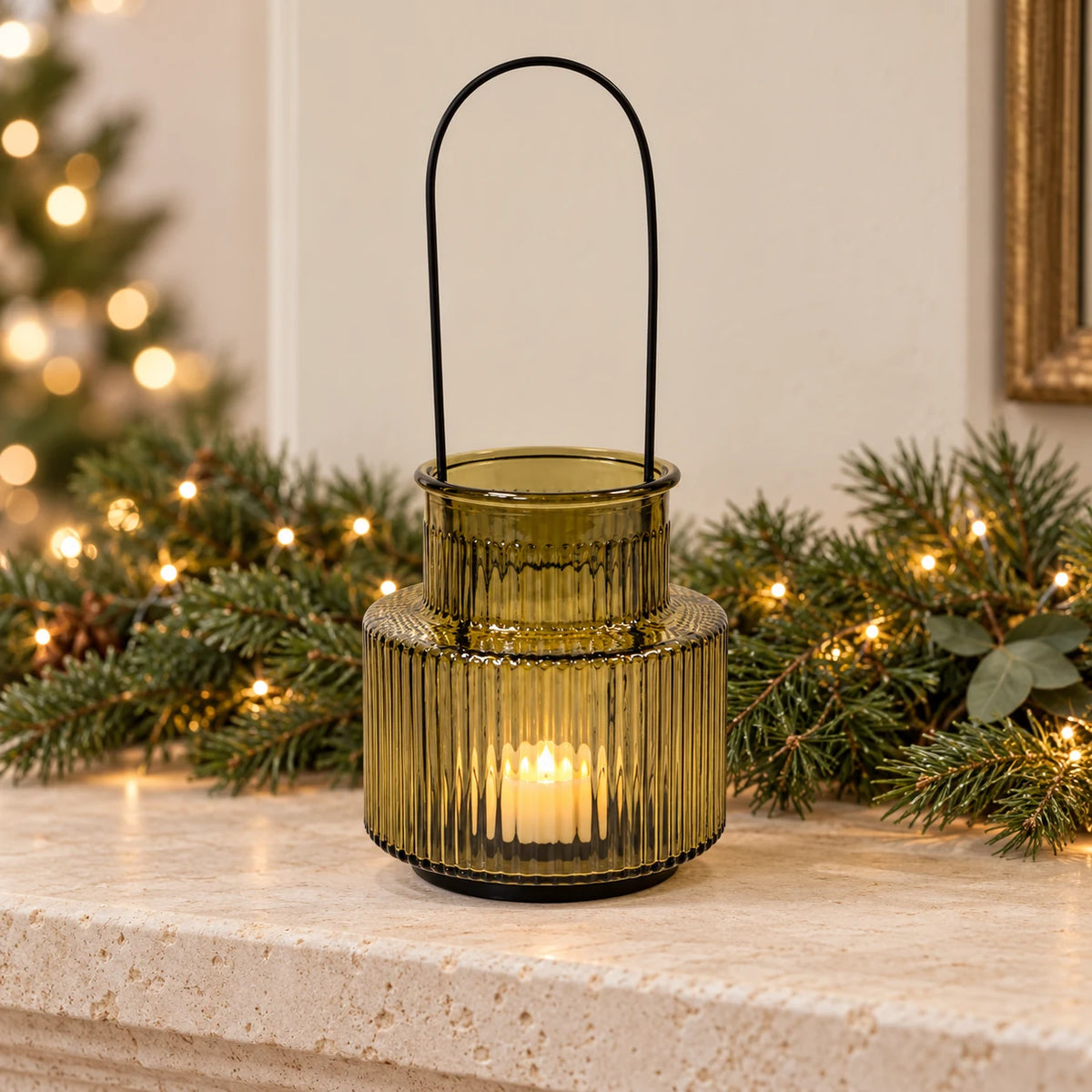 Olive green glass candle holder styled on a mantel with festive pine garland