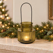 Olive green glass candle holder styled on a mantel with festive pine garland