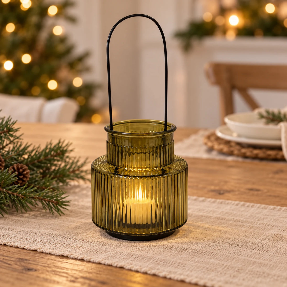 Large olive green candle holder with glowing votive on a neutral Christmas dining table