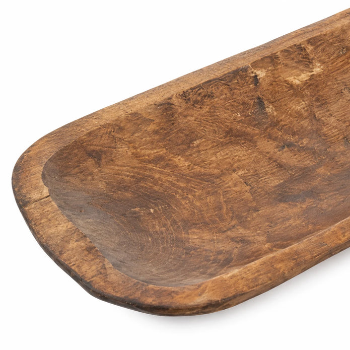 Close-up of the large rustic dough bowl’s rounded rim and hand-carved brown wood texture.