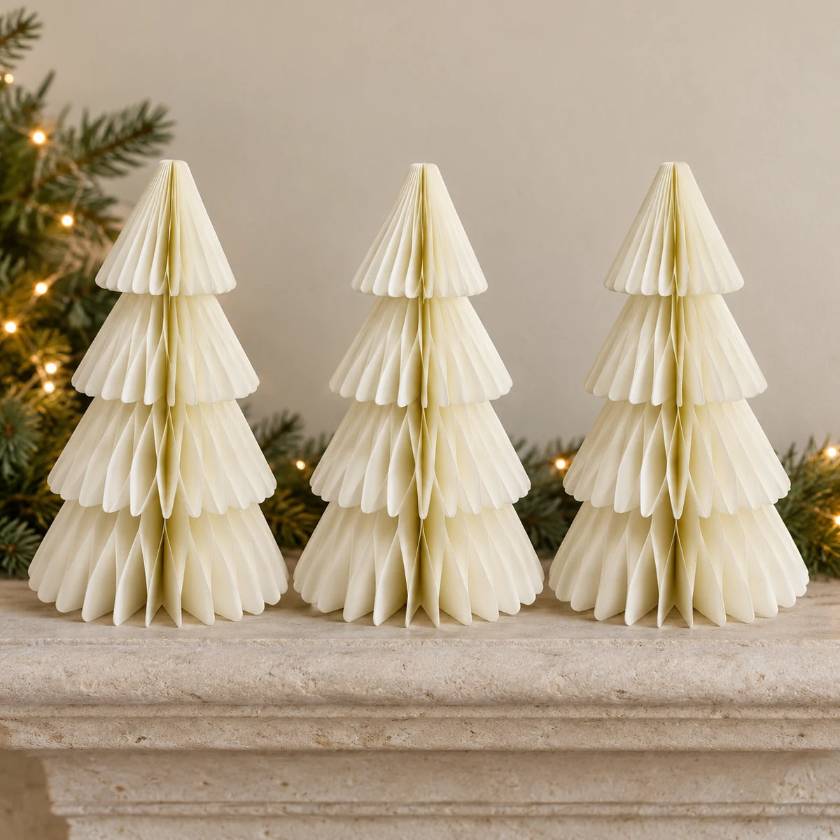 Three equal-sized winter white paper Christmas trees side by side on a stone mantel.