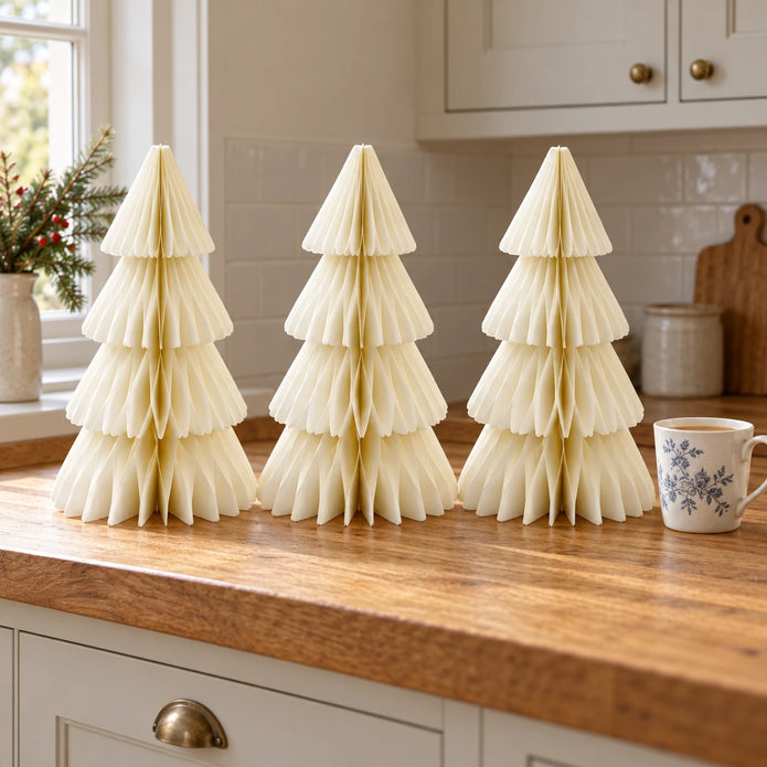 Set of three 30cm winter white paper trees beside a mug of tea on a kitchen counter.