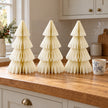Set of three 30cm winter white paper trees beside a mug of tea on a kitchen counter.