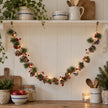 LED pinecone and red berry garland with red bells, lit beneath a kitchen shelf
