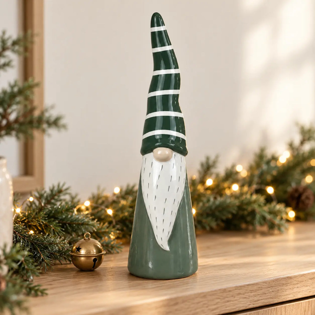 Tall green and white ceramic gonk on an oak console with Christmas greenery and fairy lights; props not included