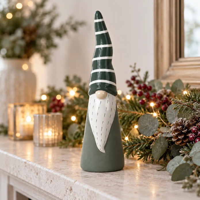 Tall ceramic Christmas gonk on a pale stone mantel with festive foliage; props not included