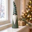 Tall green and white ceramic gonk on a winter windowsill with a gift and spruce; props not included
