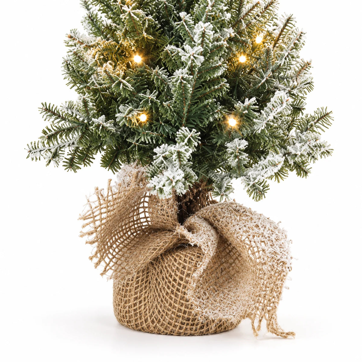 Close-up of frosted Christmas tree branches, lights and loosely gathered hessian base