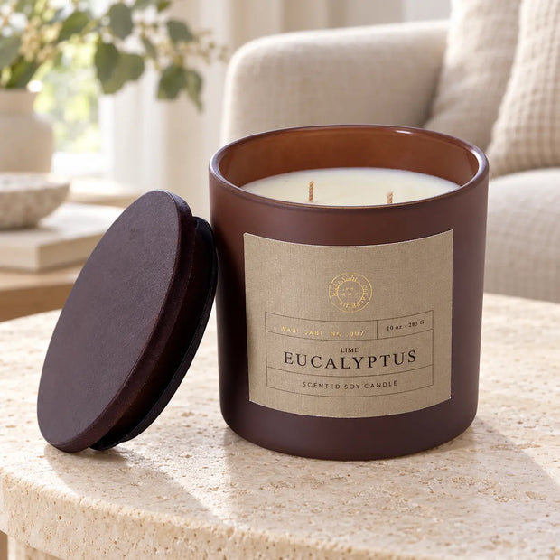 Lime and eucalyptus candle in a brown jar with lid on a pale stone side table