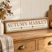 Long Autumn Market Pumpkin Sign on an oak sideboard with a ceramic vase.