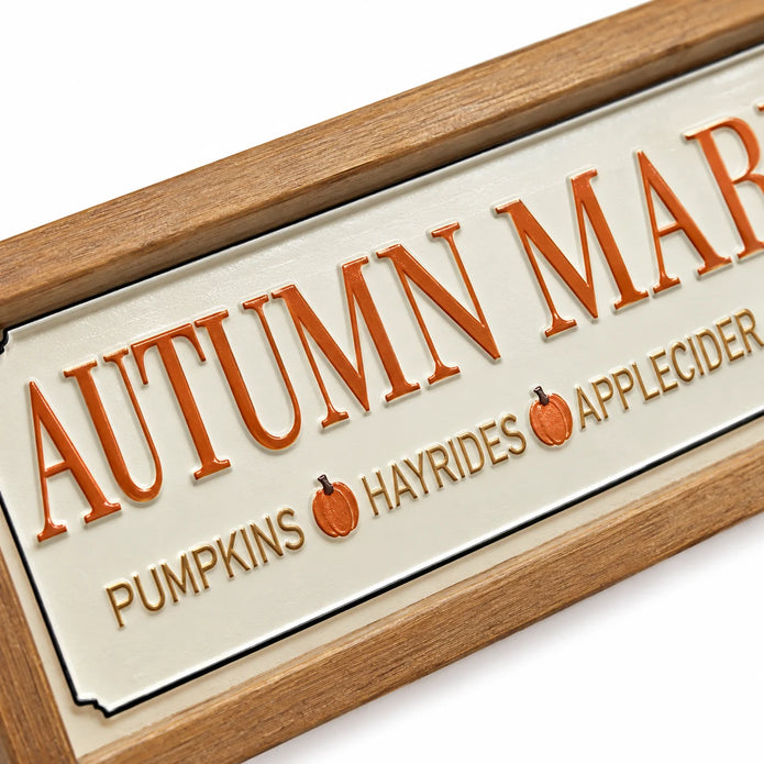 Close-up of raised lettering and cream metal surface on Long Autumn Market Pumpkin Sign.