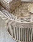 Lows rattan round side table with a natural woven surface and wooden legs, ideal for living room or patio decor.