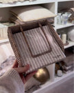 Lows rattan napkin holder with weight for kitchen and dining, featuring a natural woven design and sturdy base for holding napkins.