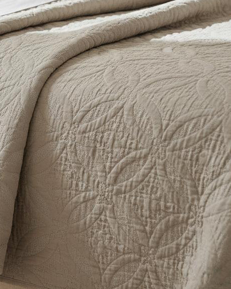 Malini Amity beige king size quilted bedspread on neatly made bed, showcasing soft furnishings and elegant bedding design.