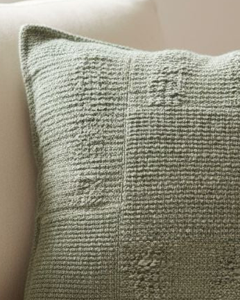 Olive green textured square cushion cover from Malini soft furnishings, showcasing a cozy fabric with a subtle pattern.