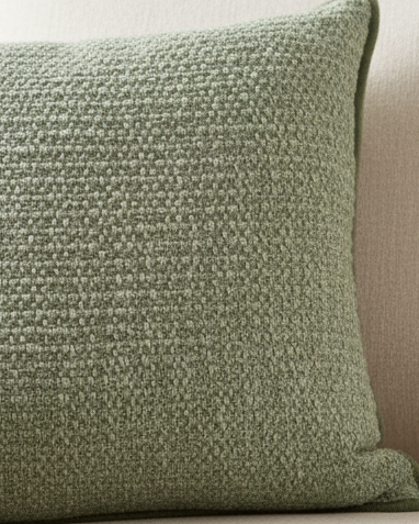 Sage green textured cushion cover from Malini's soft furnishings collection, showcasing a cozy, patterned fabric with a subtle sheen.