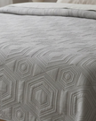 Malini Dorchester Grey Geometric Quilted Bedspread on a double bed, showcasing soft furnishings with a modern geometric pattern.