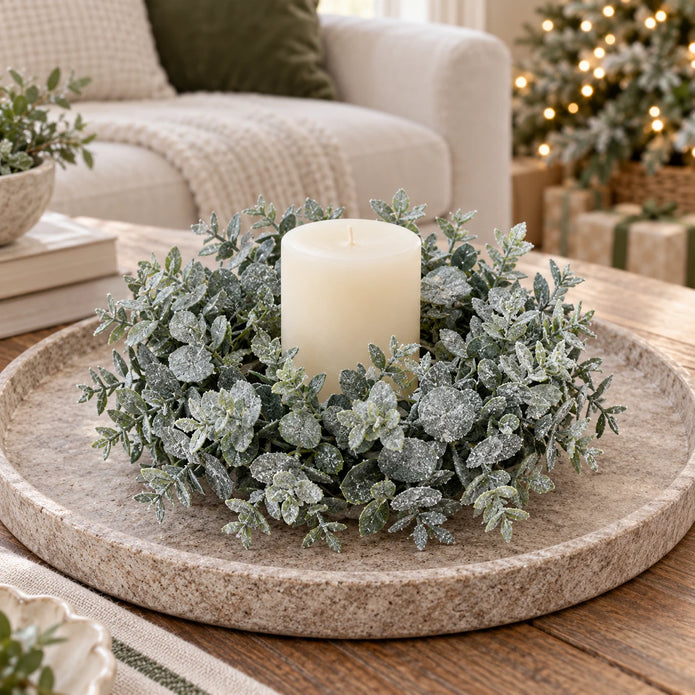 Frosted eucalyptus candle wreath around an unlit pillar candle on a stone coffee-table tray; accessories not included.