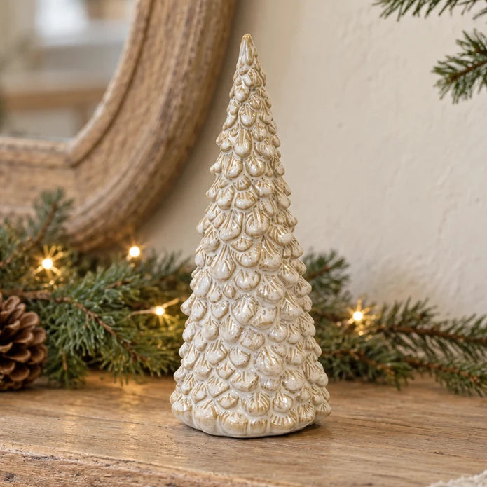 Medium cream glazed layered ceramic Christmas tree on a rustic oak console with festive greenery