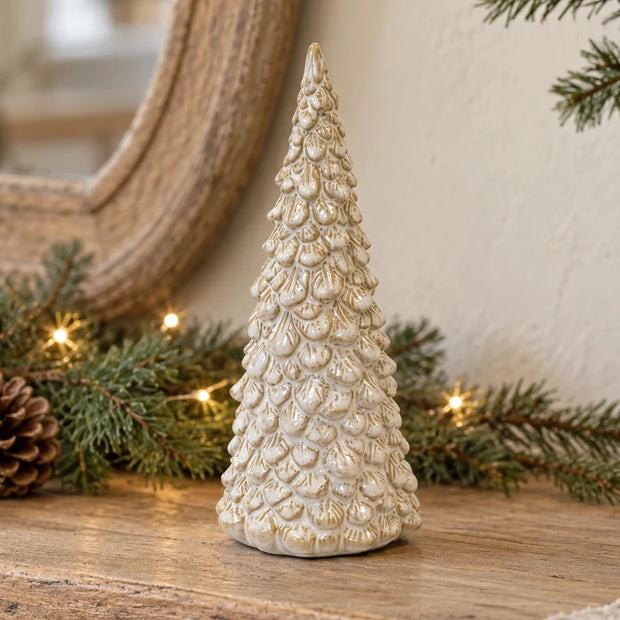 Medium cream glazed layered ceramic Christmas tree on a rustic oak console with festive greenery