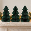 Three equal-sized green paper Christmas trees side by side on a stone mantel.