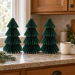 Set of three 25cm green paper trees beside a mug of tea on a kitchen counter.