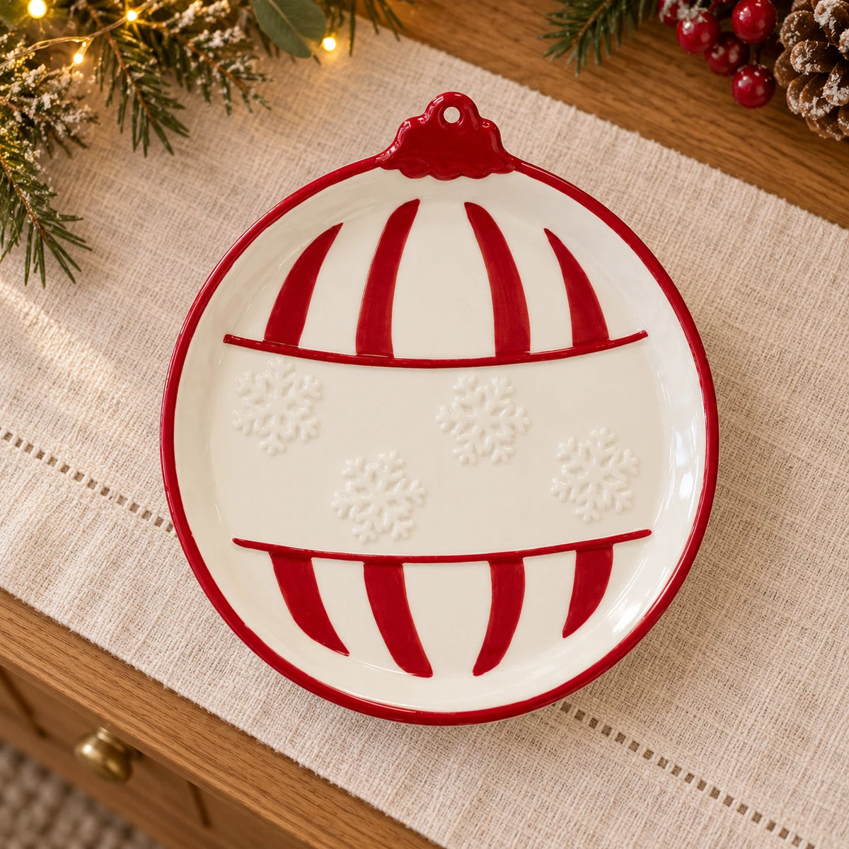 Medium red Christmas bauble plate by Satchville with a traditional design, shown on a linen-covered sideboard.