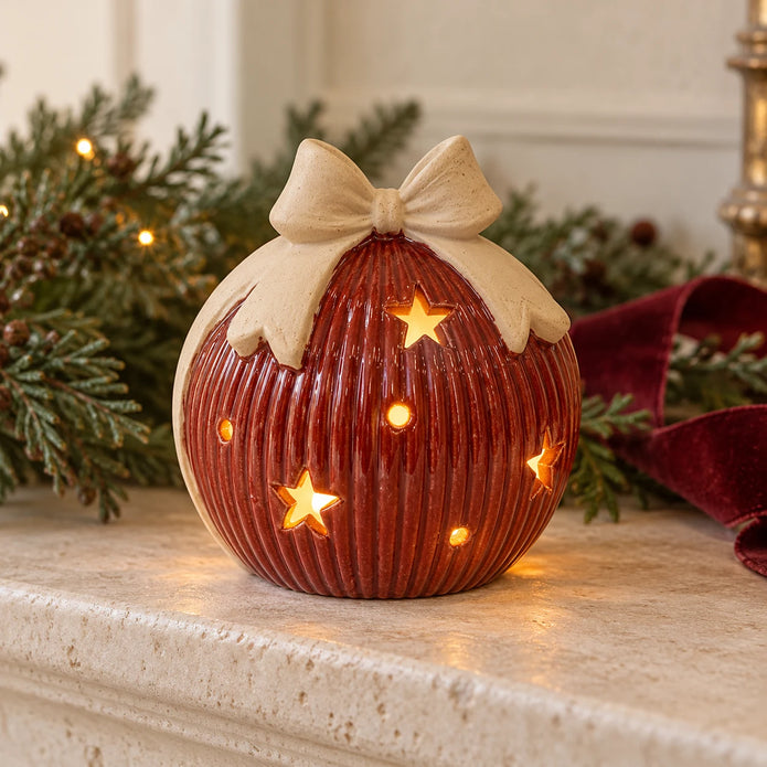 Red ceramic light-up bauble with bow displayed on a pale Christmas mantel