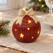 Small glowing red ceramic bauble styled on a linen Christmas table
