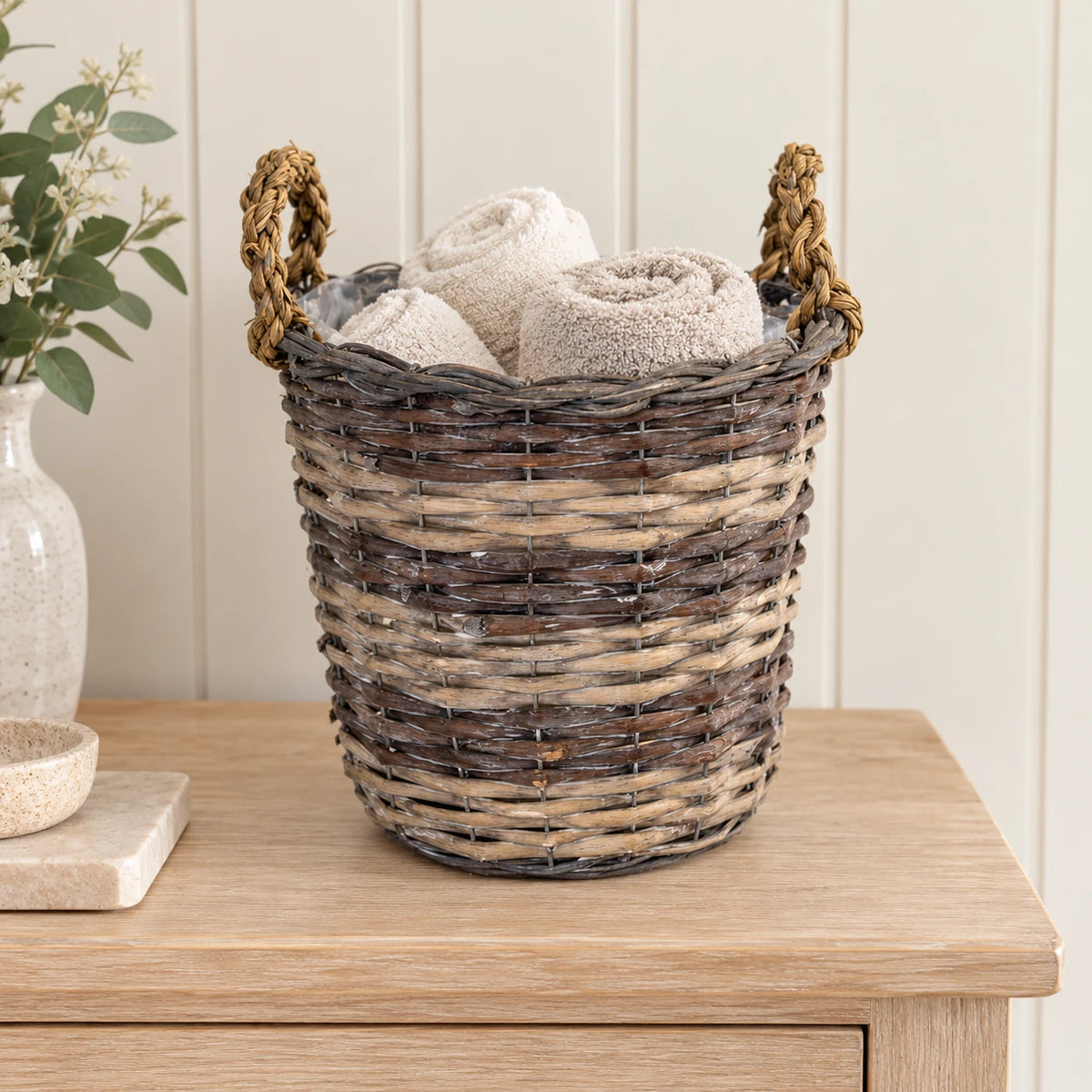 Meon round split-willow basket with small rolled neutral guest towels on oak console