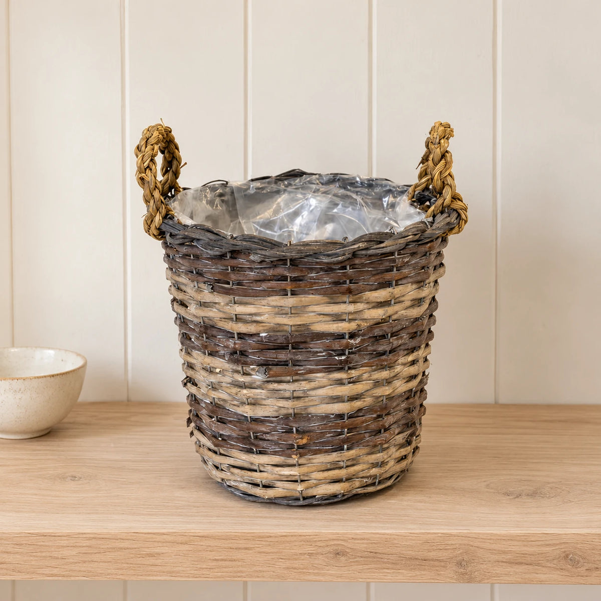 Empty Meon round basket with clear liner on a pale oak shelf