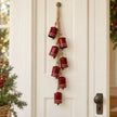 Glossy red cowbell garland hanging on a white door
