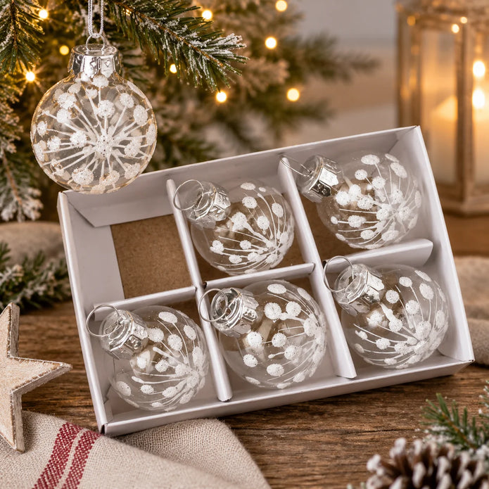 Mini clear glass white snowflake baubles in a divided gift box beside Christmas greenery, set of six