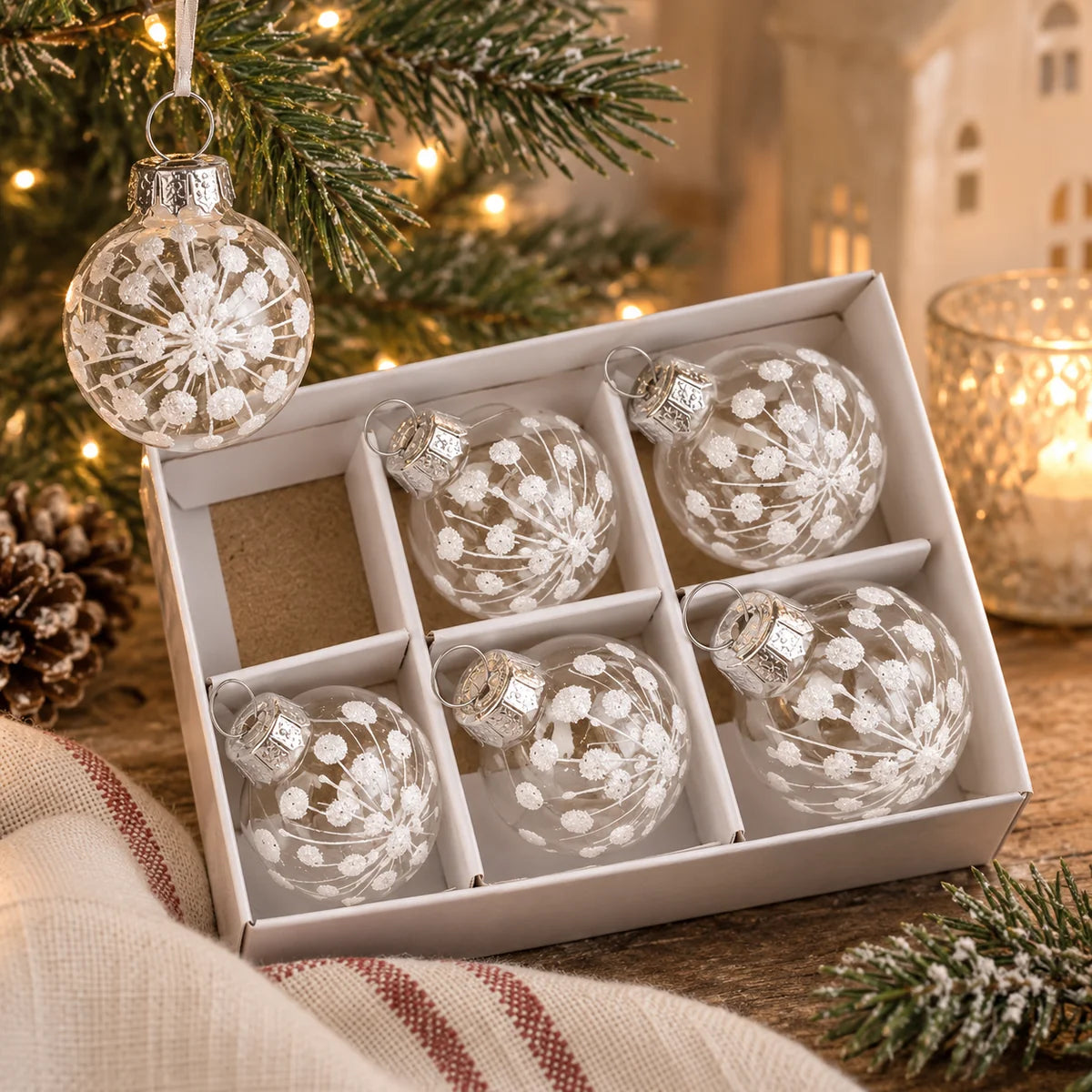 Mini white snowflake clear glass baubles in box styled with Christmas greenery and warm lights
