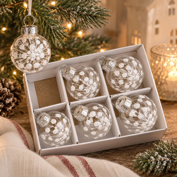 Mini white snowflake clear glass baubles in box styled with Christmas greenery and warm lights