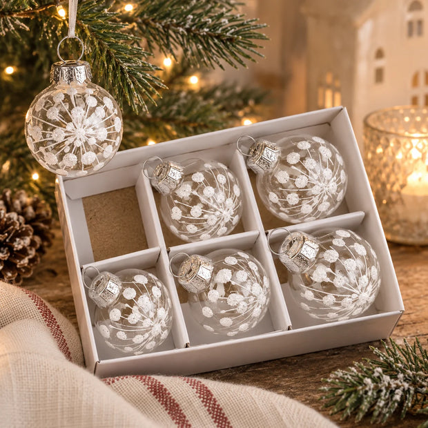 Mini white snowflake clear glass baubles in box styled with Christmas greenery and warm lights
