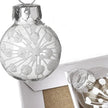 Close-up of white glitter snowburst design on clear mini glass Christmas bauble with silver cap