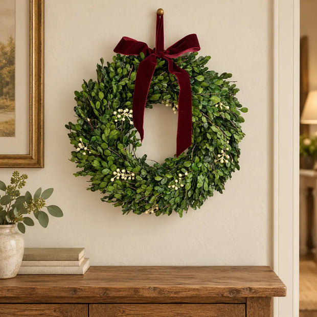 Mistletoe Christmas wreath with burgundy bow above an oak hallway console